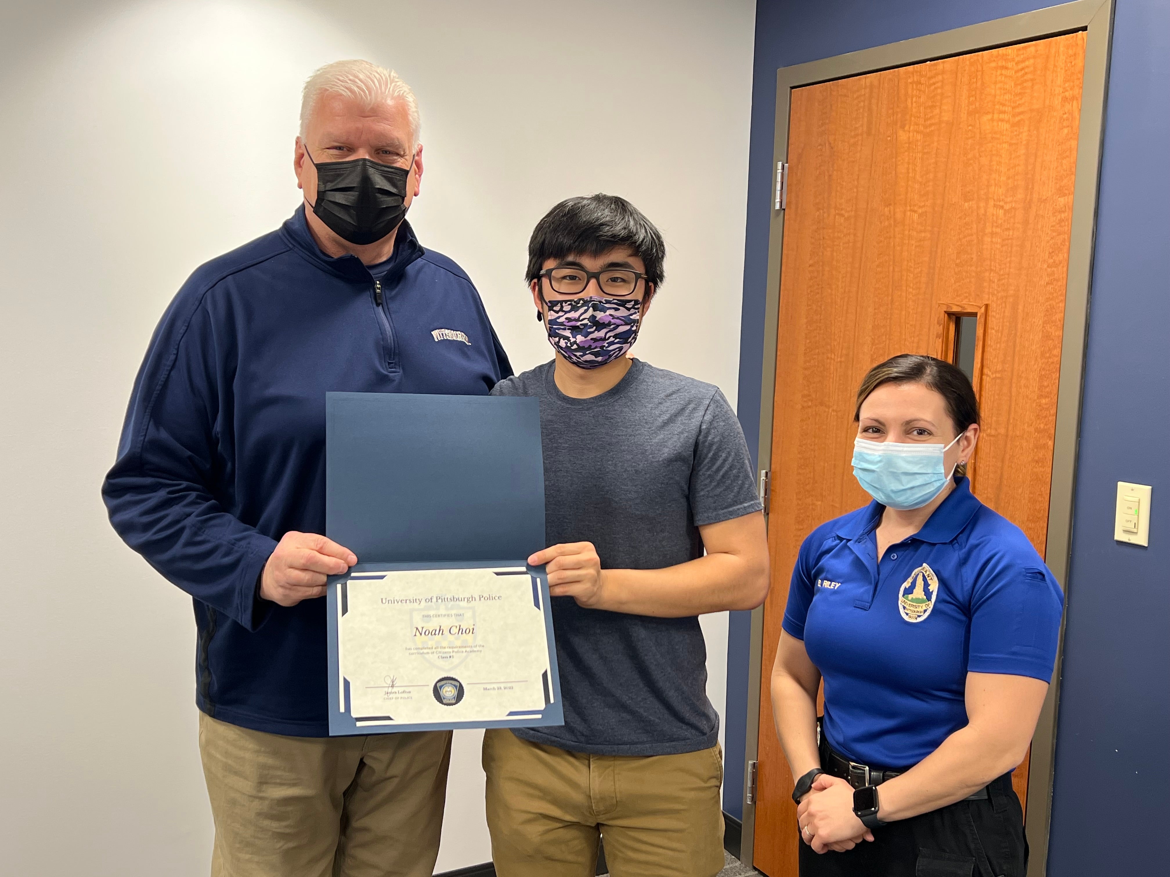 Noah Choi receives his graduation certificate from Pitt Police Chief James Loftus and Lt. Brooke Riley.
