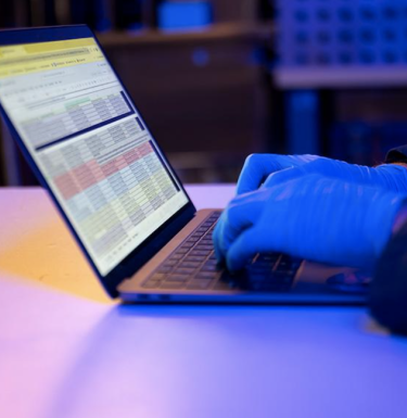 Person wearing blue gloves typing on a laptop